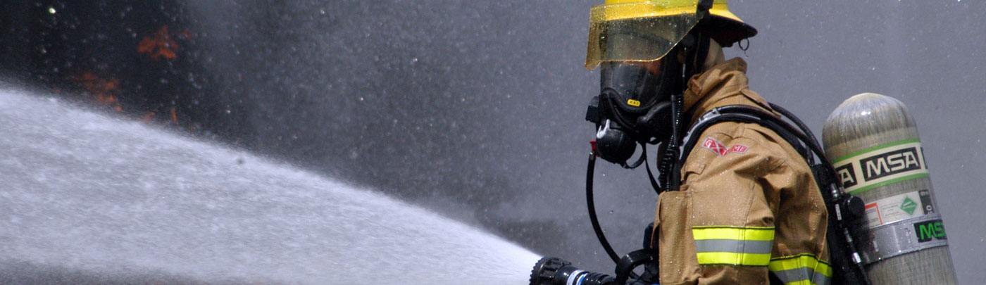 Firefighter in breathing apparatus spraying water